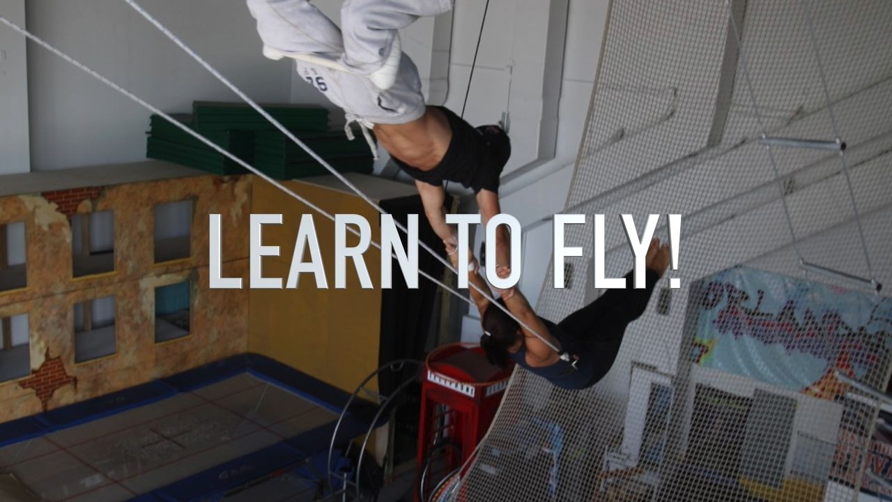 Two flyers on the flying trapeze over the net